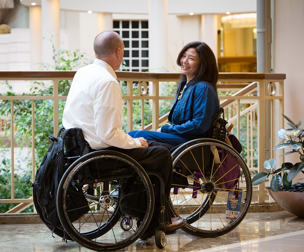 A man and a woman in wheelcheers talking